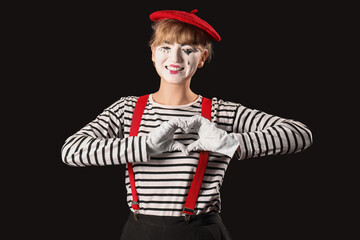 Female pantomimist making heart with her hands on black background