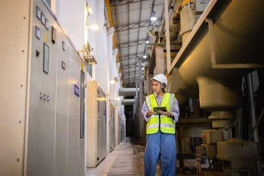 Engineer inspects electric grid field wearing safety helmet and vest near insulated switchgear and gas equipment in gis facility ensuring operational safety and efficiency
