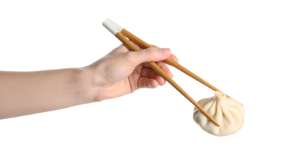 A hand carefully holds a steamed dumpling with chopsticks, ready to eat.