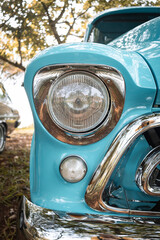 Front of an old pickup truck with chrome details and round headlight.