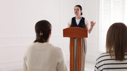 Woman giving public speech at lectern in front of audience indoors - Powered by Adobe