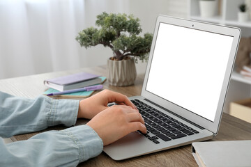 Fototapeta premium Woman with modern laptop, notebooks and bonsai working at wooden table in room, closeup