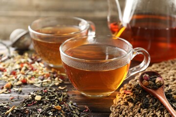 Refreshing herbal tea and dry leaves on wooden table, closeup