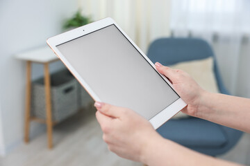Woman with modern tablet at home, closeup