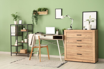 Interior of stylish office with workplace, shelf unit and plants