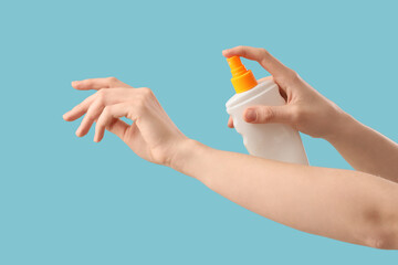 Woman applying sunscreen cream on blue background