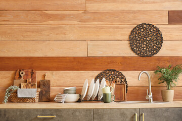 Counters with sink and utensils near wooden wall in kitchen