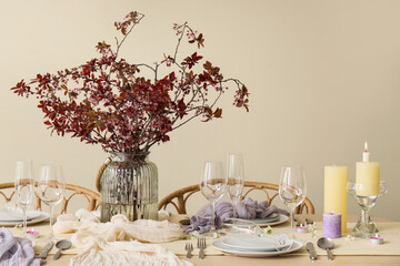 Table setting with blossoming branches and burning candles in room