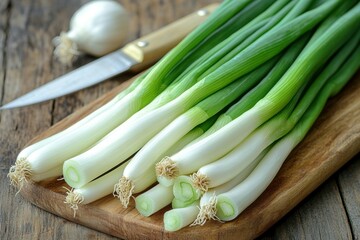 Fresh green onions on a wooden cutting board with a knife