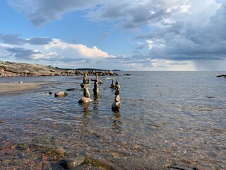 Steinskulpturen / Steinm&auml;nnchen / Naturobjekte / Naturkunst mit Steinen an der K&uuml;ste im Wasser am See / Meer in Skandinavien / Schweden