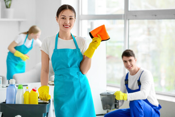 Female Asian janitor with trolley and her team cleaning in office