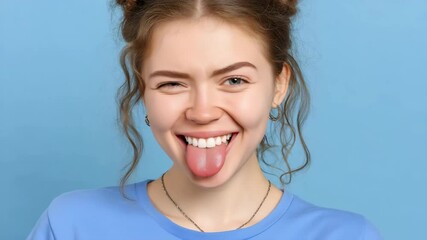 A cheerful young woman sticks out her tongue against a bright blue background. Concept of fun self expression - Powered by Adobe