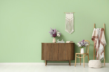 Interior of living room with chair, commode and lilac flowers in vases