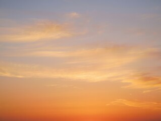 Fototapeta premium Tranquil sky during sunset with soft orange and yellow hues blending into light blue with wispy clouds