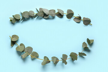 Frame made of green eucalyptus branches on blue background