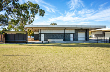 A contemporary sports pavilion or multipurpose building with a covered outdoor veranda. The facility overlooks a large grassy field. Modern public sporting infrastructure in an Australian suburb.