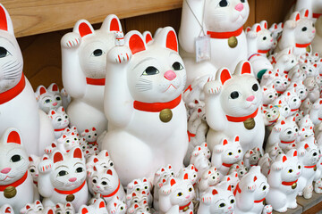 Tokyo, Japan - Sep 30 2024, A close-up view of many multi-sized white beckoning cat figure of Maneki neko with red ears and noses displayed at Gotokuji Temple, without people, at daytime, Tokyo, Japan