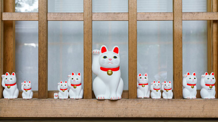 Tokyo, Japan - Sep 30 2024, A close-up view of many multi-sized white beckoning cat figure of Maneki neko with red ears and noses displayed at Gotokuji Temple, without people, at daytime, Tokyo, Japan
