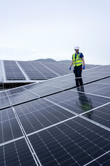 Engineers install solar panels on a wet rooftop during cloudy weather
