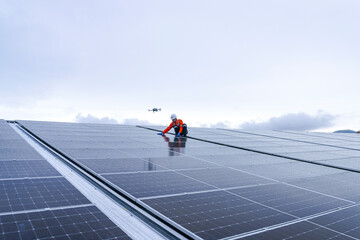 Engineer inspects wet solar panels on a rooftop under overcast sky