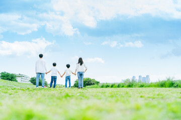 青空の草原を歩く家族