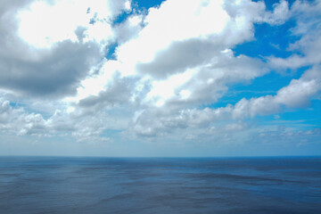 Obraz premium Tranquil Ocean Horizon with a Dynamic Sky: A peaceful image of the ocean stretching out to the horizon under a blue sky with both clear patches and dramatic cloud formations.