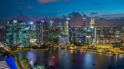 Aerial view of Singapore business district skyscrapers at evening with water reflections day to night timelapse