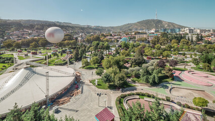 Aerial timelapse of Rike Park, a modern urban park in Tbilisi's Old Town with green trees and lawns. The Bridge of Peace in the background. Georgia © HyperlapsePro