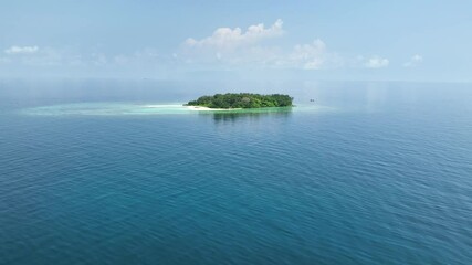Aerial view of a small, uninhabited tropical island near Karimunjawa, featuring pristine beaches, lush vegetation, and surrounding coral reefs.