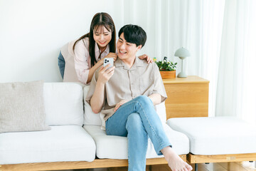 Obraz premium リビングでスマホを見るカップル