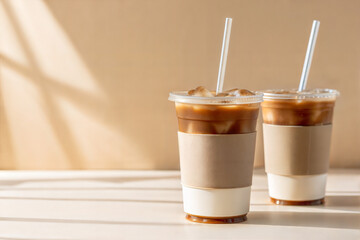 Cold coffee plastic cup mockup with ice cubes and straws, two cups on minimal beige background

