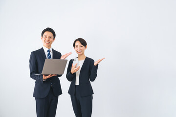 ノートパソコンとスマホを持って案内する男女ビジネスパーソン