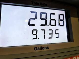 a digital display at a gas pump at night reading the price per gallon in US dollars. energy and the economy design element. price at the pump concept.