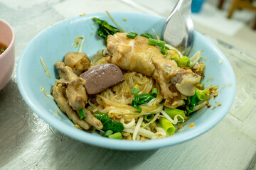 A chicken noodle served by a street food vendor with drumstick, vegetables and coagulated chicken blood in Thailand
