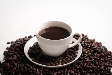 Freshly brewed black coffee in a white cup beside roasted beans on rustic table, capturing morning aroma, warmth, and cozy atmosphere.