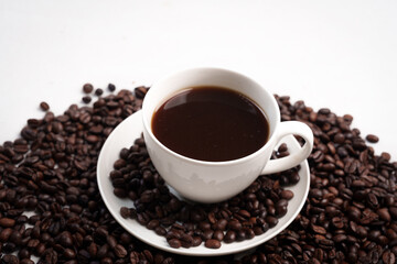Freshly brewed black coffee in a white cup beside roasted beans on rustic table, capturing morning aroma, warmth, and cozy atmosphere.