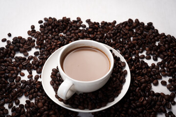 Freshly brewed black coffee in a white cup beside roasted beans on rustic table, capturing morning aroma, warmth, and cozy atmosphere.