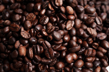 Close-up of roasted brown coffee beans piled together, showcasing rich texture, aroma, and freshness on a white studio background.
