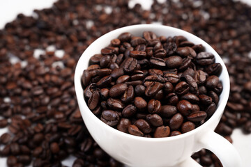 Close-up of roasted brown coffee beans piled together, showcasing rich texture, aroma, and freshness on a white studio background.