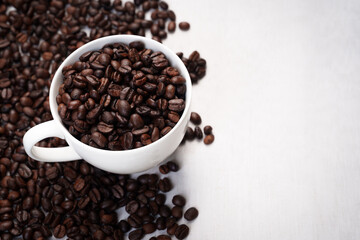 Close-up of roasted brown coffee beans piled together, showcasing rich texture, aroma, and freshness on a white studio background.
