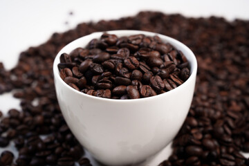 Close-up of roasted brown coffee beans piled together, showcasing rich texture, aroma, and freshness on a white studio background.