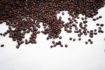 Close-up of roasted brown coffee beans piled together, showcasing rich texture, aroma, and freshness on a white studio background.