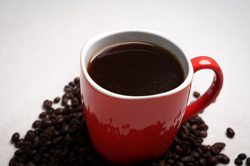 Freshly brewed black coffee in a white cup beside roasted beans on rustic table, capturing morning aroma, warmth, and cozy atmosphere.