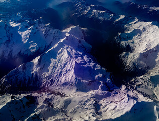 An aerial shot of the Swiss Alps mountain range on a sunny day with blue skies