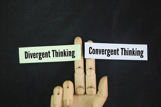 Hand and colored paper with words Two prominent types of thinking are divergent thinking and convergent thinking.