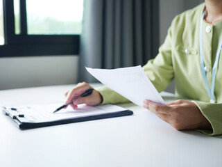 Businesswoman is reading a resume to evaluate a job applicant. Sitting reading a resume to hire candidates, analyzing information before an interview. Recruitment concept.