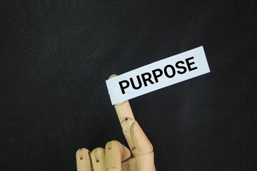 Hand and colored paper with the word purpose. the reason for which something is done or created or...