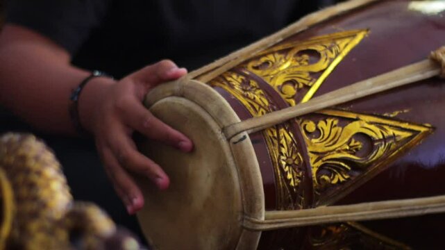 close up of a gamelan player hitting Kendang