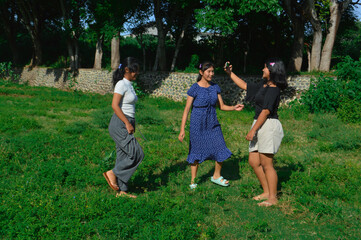 Obraz premium As they walk through the field, one of the girls lifts her phone to take a selfie while the others follow.