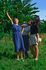 Fototapeta premium They strike another pose while snapping a selfie together, goats grazing in the background.
